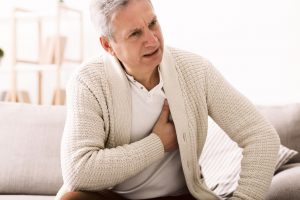 Older man holding onto his chest from heart burn