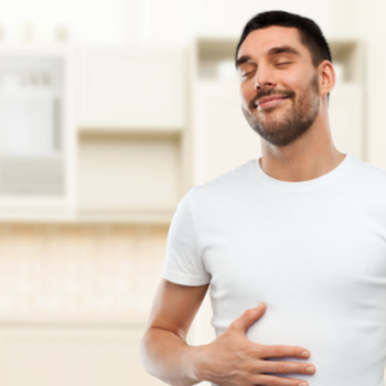 happy full man touching his tummy over kitchen