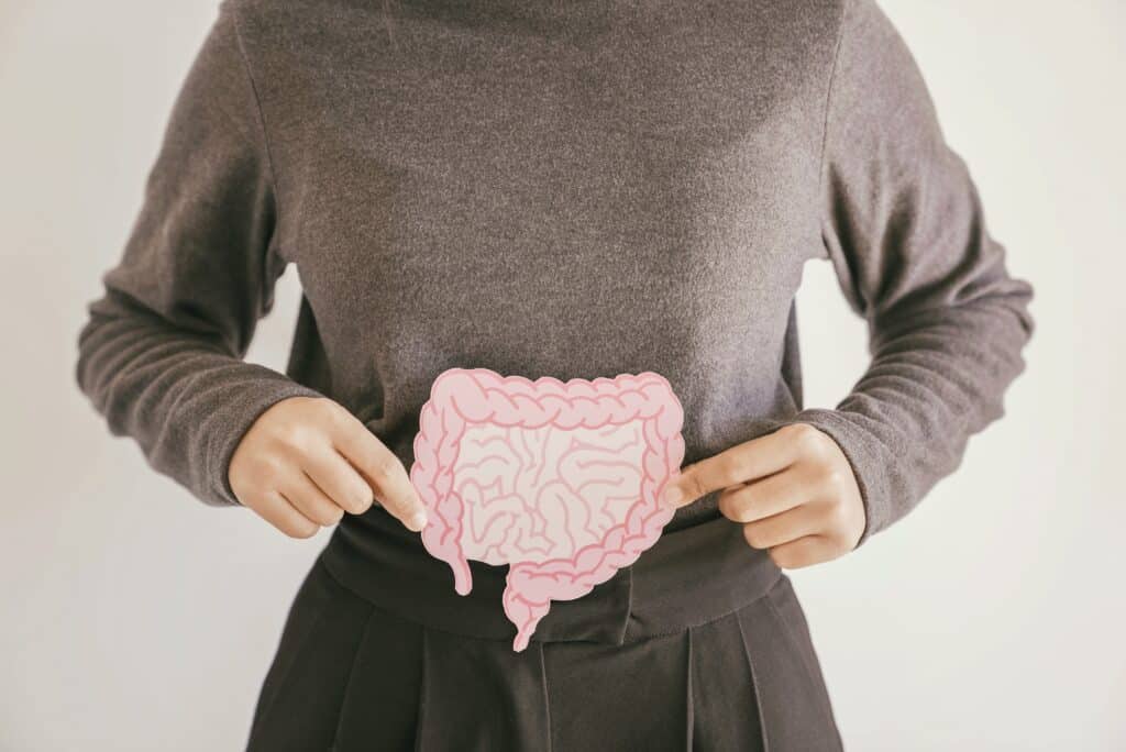 A cropped shot of a woman holding a picture of intestines in front of her torso